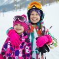 Portrait of two little girl in  ski helmet and mask in winter resort