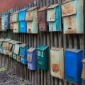 Set of old mailboxes with rust attached to the fence