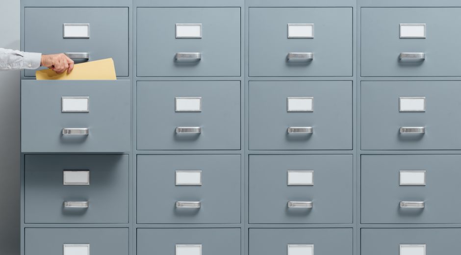 Office worker taking a file from a filing cabinet drawer, business and administration concept